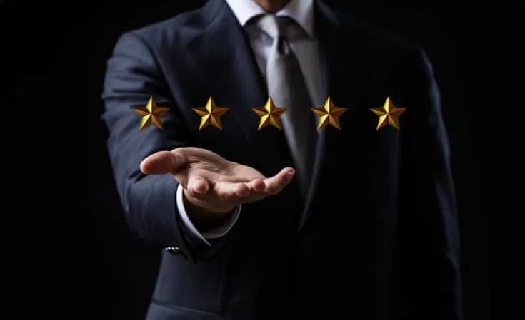 A well dressed consultant has 5 gold stars suspended over his hand.